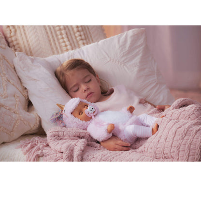 Child sleeping with a doll wearing a pink outfit on a soft surface