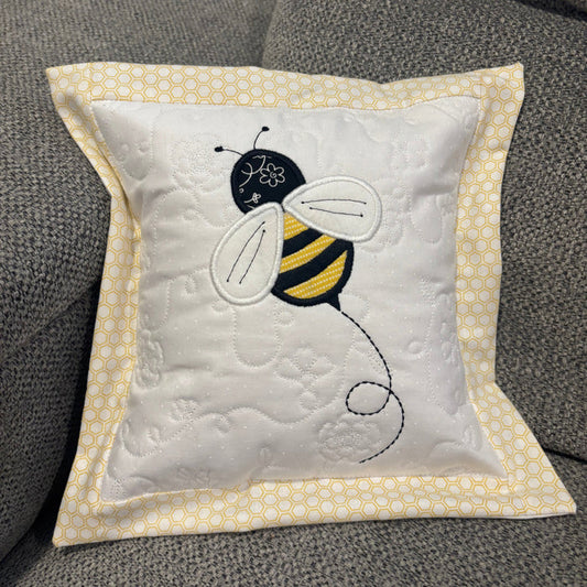 Decorative pillow with a bee design on a textured surface