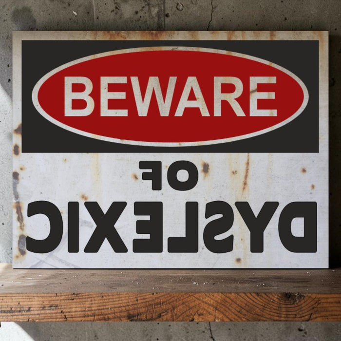 Rustic warning sign with 'Beware of Dyslexic' text on a wooden surface.