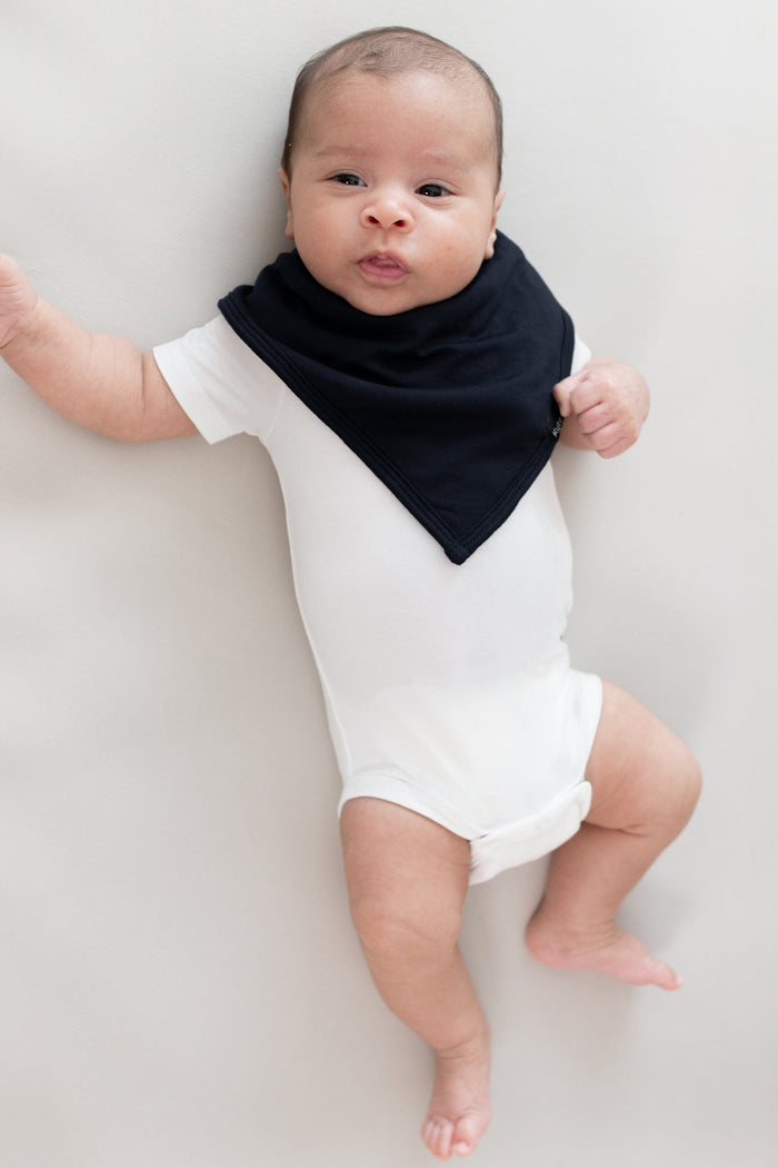 Infant laying on its back wearing a Bib in Midnight and Short Sleeve Bodysuit in Cloud