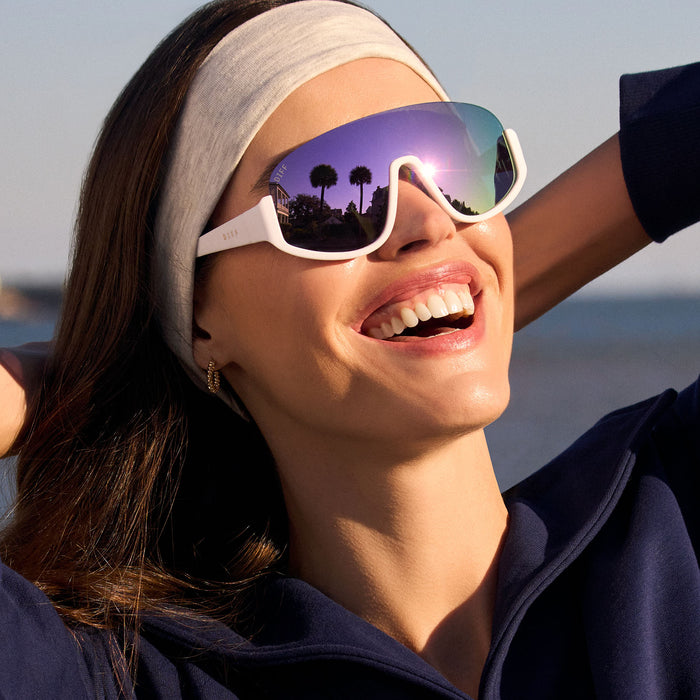 on model - female wearing diff sport featuring the blazer shield sunglasses with a matte white frame and lavender mirror polarized lenses angled view