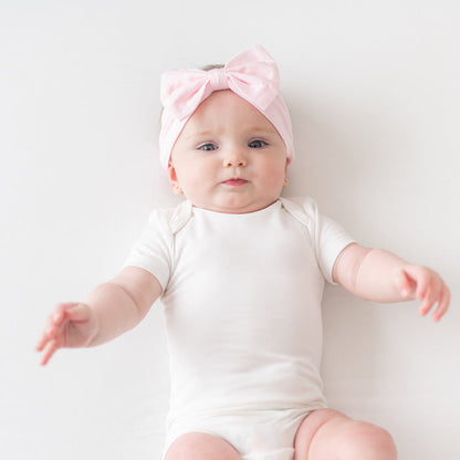 Baby wearing cloud bodysuit and Bow Headband in Sakura pink