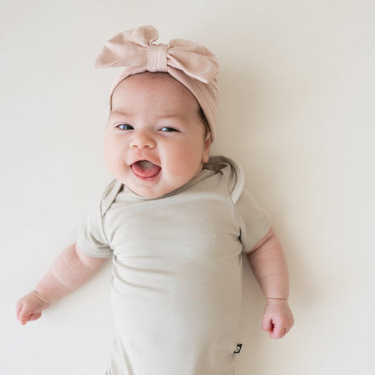 Baby wearing Bow Headwrap in Blush with tan bodysuit