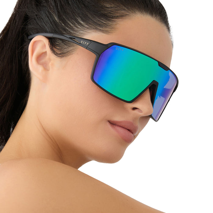 on model - female wearing diff sport featuring the charge shield sunglasses with a matte black frame and green mirror polarized lenses side view