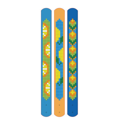 Set of three vertical slap bracelets by Diamond Dotz—Gone Troppo Bracelets—with pixel art pumpkins, wavy green and yellow shapes, and yellow-orange flowers. Great for kids' crafts or as a Diamond Dotz kit accessory.
