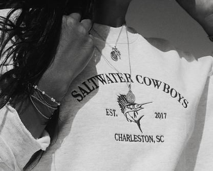 White sweatshirt with 'Saltwater Cowboys' branding worn by a person.