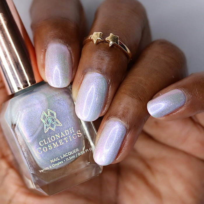 Close-up of nails painted with Boneyard Nail Lacquer on deep skin tone. Hand is holding polish bottle.