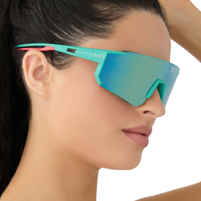 on model - female wearing diff sport featuring the heat shield sunglasses with a turquoise frame and turquoise ice mirror polarized lenses side view