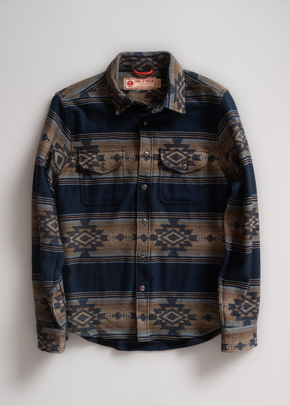 Blue and brown patterned button-up shirt with geometric designs, featuring two chest pockets, laid flat on a white background.