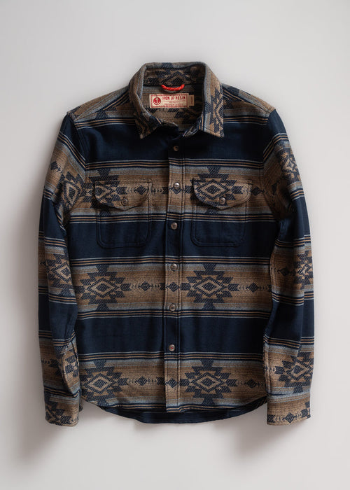 Blue and brown patterned button-up shirt with geometric designs, featuring two chest pockets, laid flat on a white background.