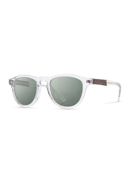 Clear-framed sunglasses with round green lenses and wooden temple accents, set against a white background.