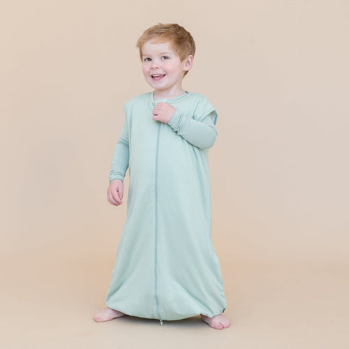toddler boy wearing a sage green sleep bag walker