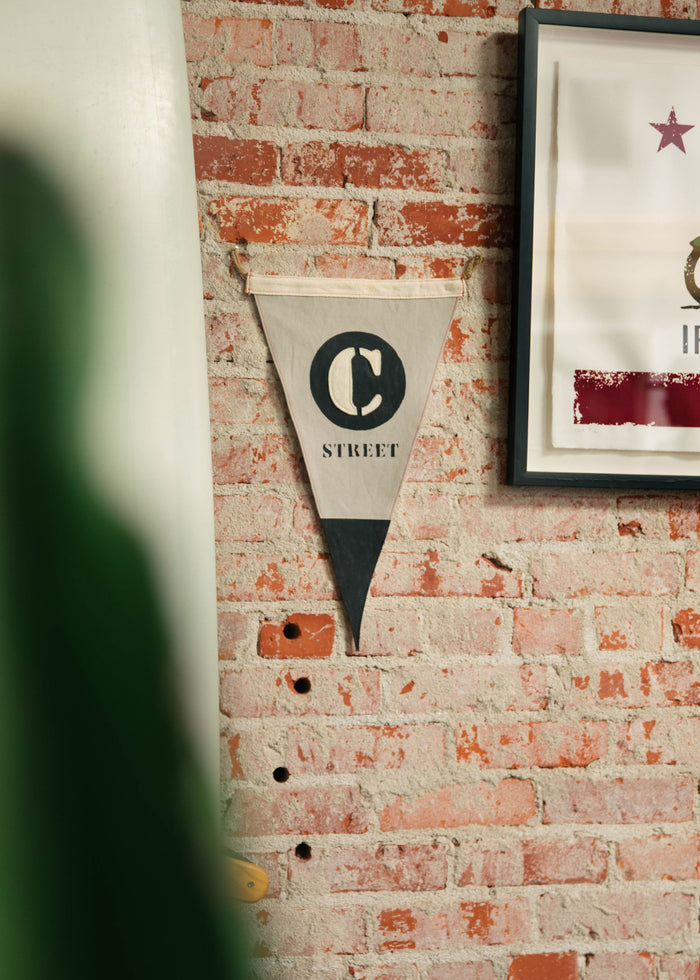 A "C Street" pennant hangs on a rustic brick wall, next to a framed artwork with a star, adding vintage charm to the decor.