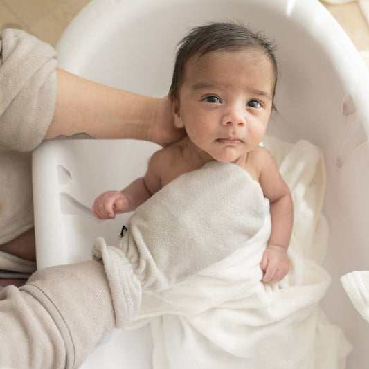 Parent bathing newborn with Terry Bath Mitt in Oat