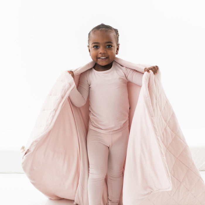 Child wrapped in Kyte Baby Toddler Blanket in Blush 2.5