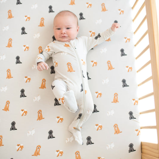 Baby wearing footie pajamas laying on Crib Sheet in Fluffy Dog